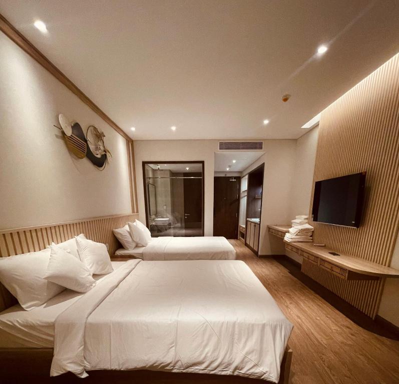a hotel room with two beds and a flat screen tv at Lighthouse Apec Mũi Né in Phan Thiet
