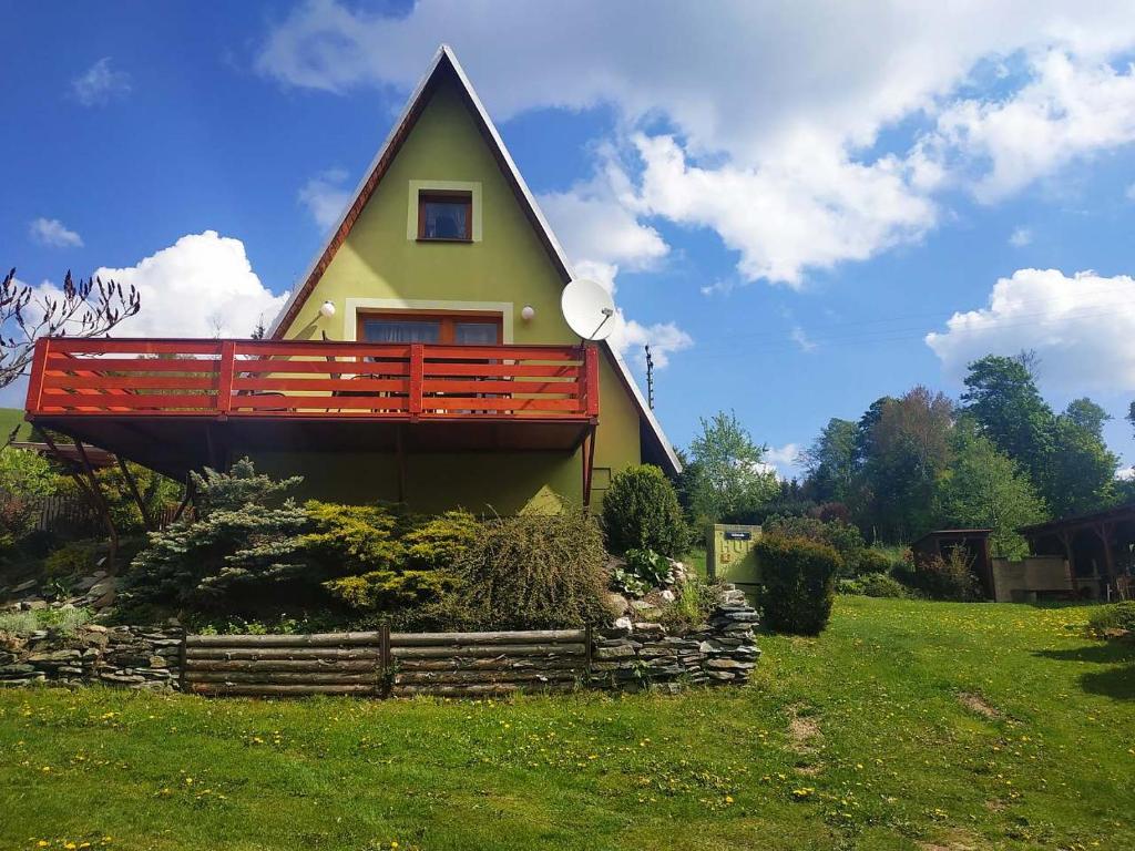 una casa con una recinzione rossa su un campo verde di Chata Sofie a Dolní Moravice