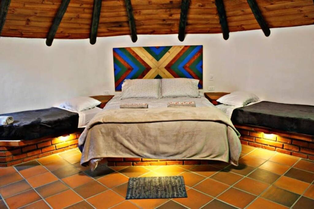 - une chambre avec un lit et une peinture murale dans l'établissement Ecohotel Buenavista, à Villa de Leyva