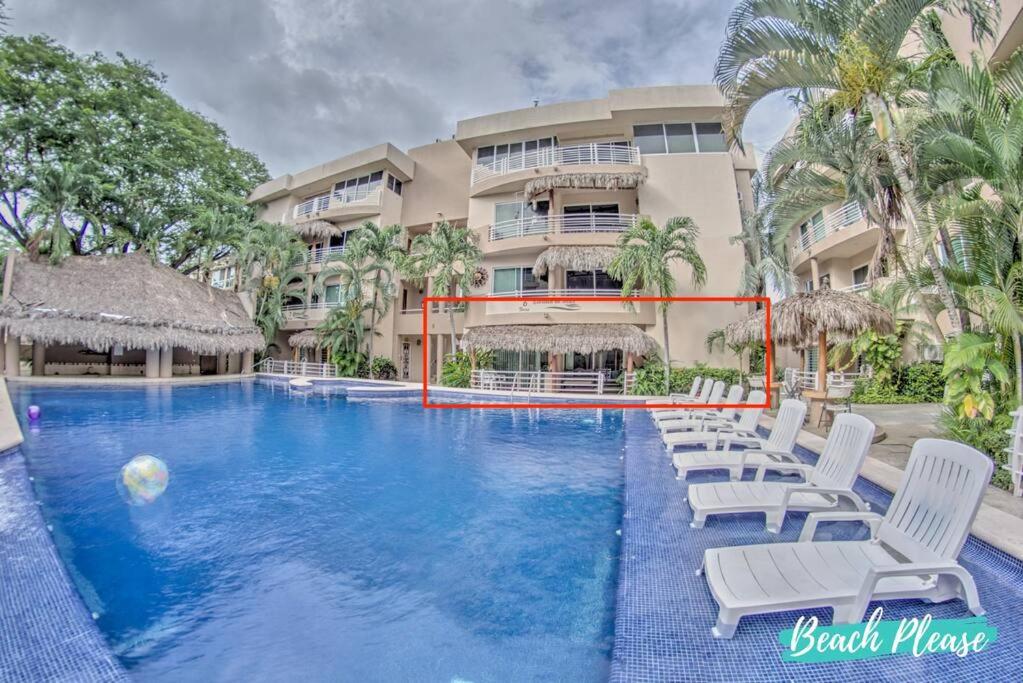 a swimming pool with white chairs and a building at Perla del Mar - Large Pool and 6 blocks to Beach in Bucerías