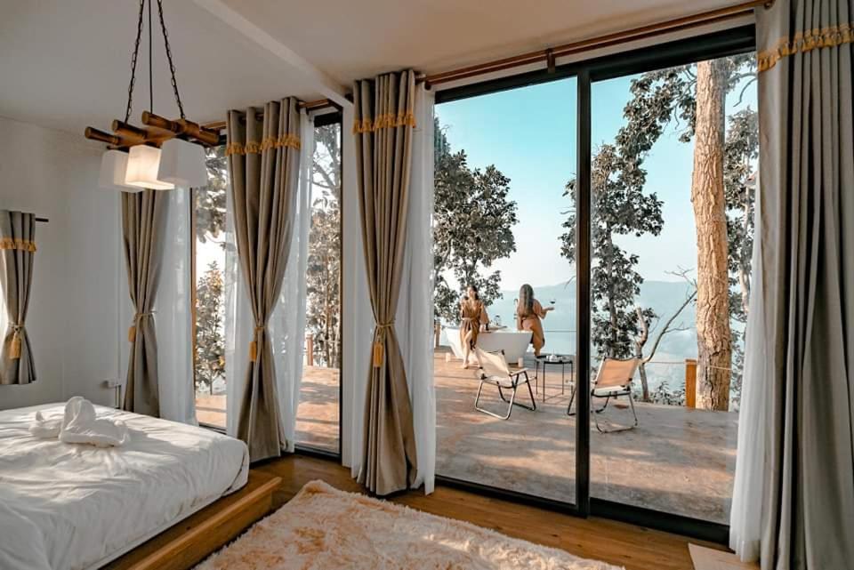 Un dormitorio con una cama y una gran ventana de cristal. en WeddingCamp Doichang บ้านพบรัก, en Ban Sam Laem
