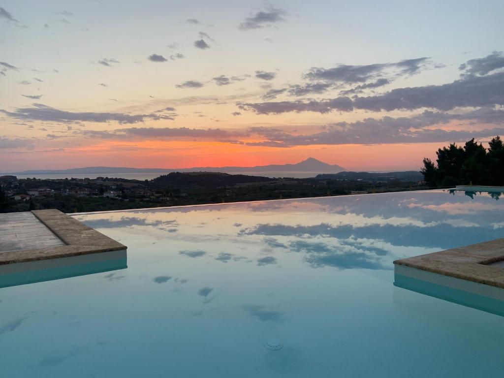 a swimming pool with a sunset in the sky at ST NIKOLA PANORAMIC SUITES HALKIDIKI in Agios Nikolaos