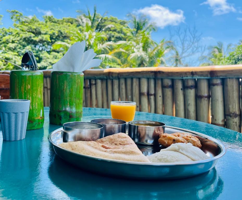 a plate of food on a table with an orange juice at Bhūma in Havelock Island