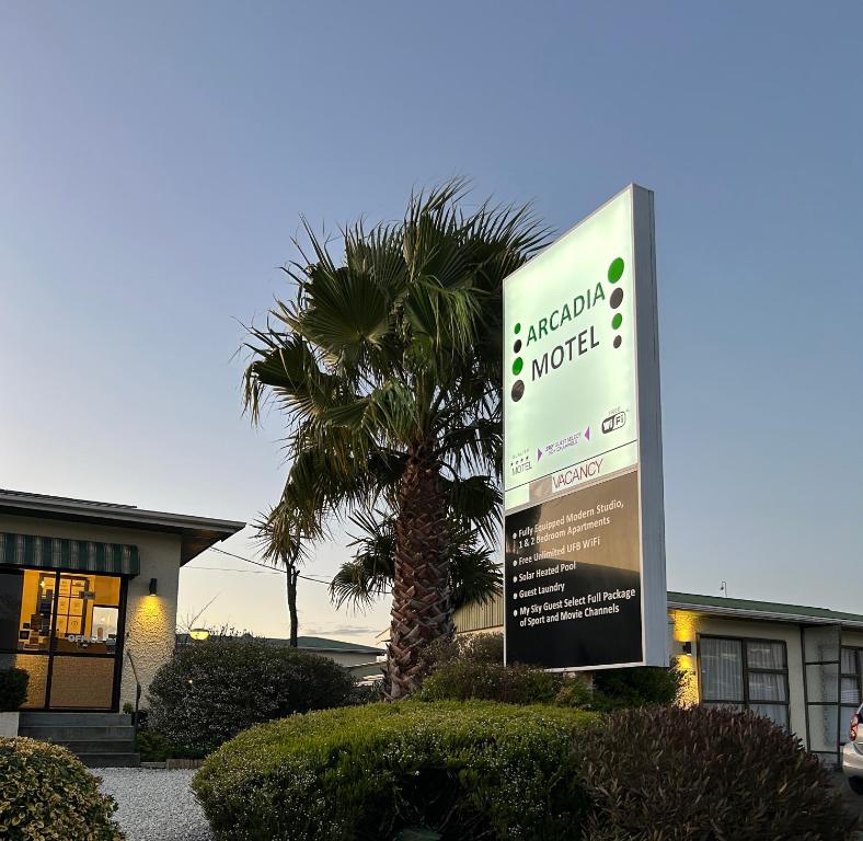 una señal frente a un edificio con una palmera en Arcadia Motel, en Nelson