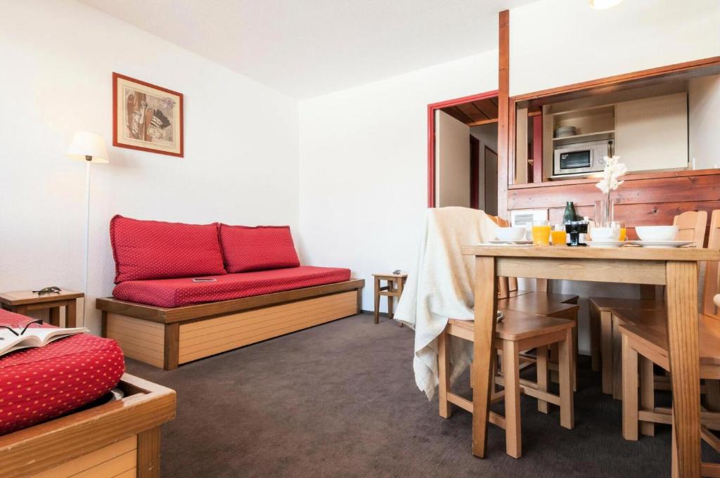un salon avec un canapé rouge et une table dans l'établissement Résidence Les Fontaines Blanches - maeva Home - Appartement 2 Pièces 5 Personnes - Confort MAE-7312, à Morzine