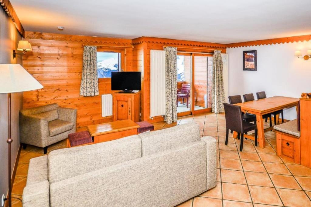 uma sala de estar com um sofá e uma mesa em Résidence Les Hauts Bois - maeva Home - Appartement 4 Pièces 8 Personnes - 82 em Aime La Plagne