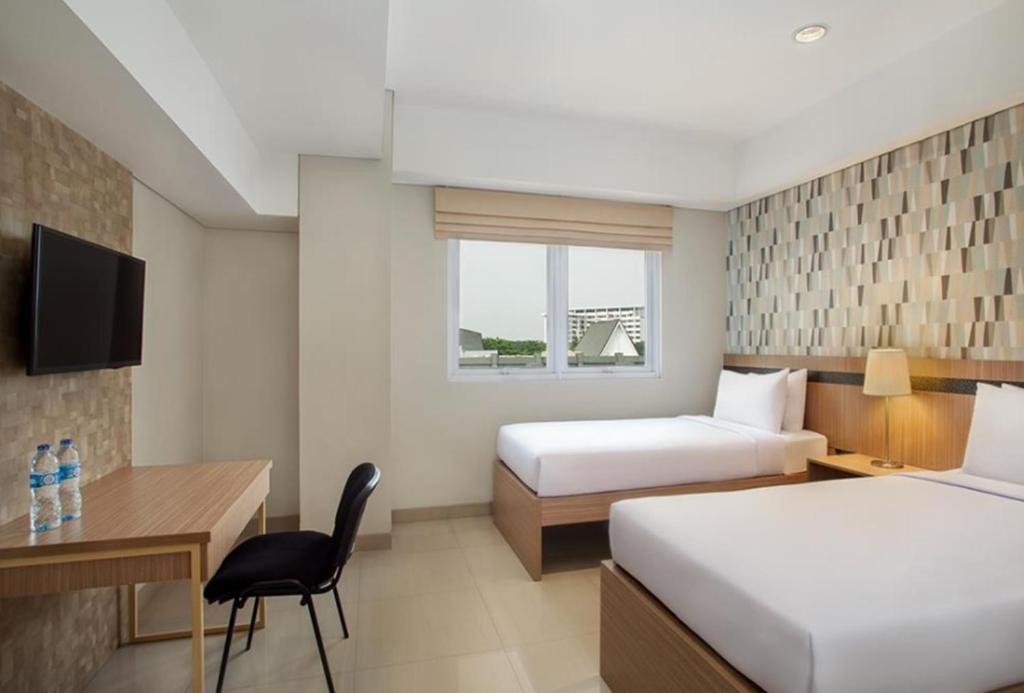 um quarto de hotel com duas camas e uma secretária em All Nite and Day Hotel Alam Sutera em Serpong