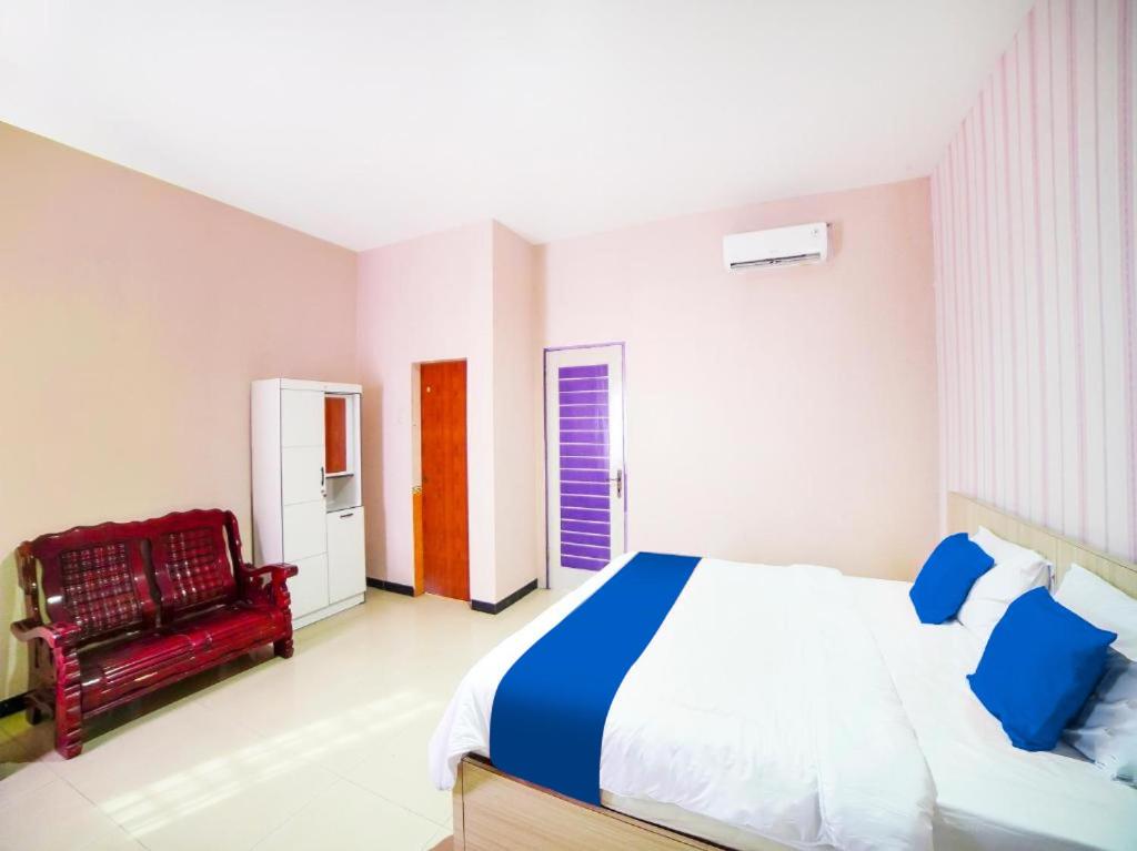 1 dormitorio con 1 cama grande y 1 silla roja en Sg Premium Guest House By Helocus, en Medan