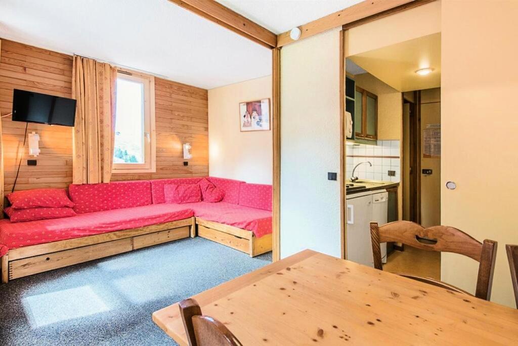 un salon avec un canapé rouge et une table dans l'établissement Résidence Les Chalets des Arolles - maeva Home - Studio 5 Personnes - Budget MAE-6424, à La Plagne Tarentaise