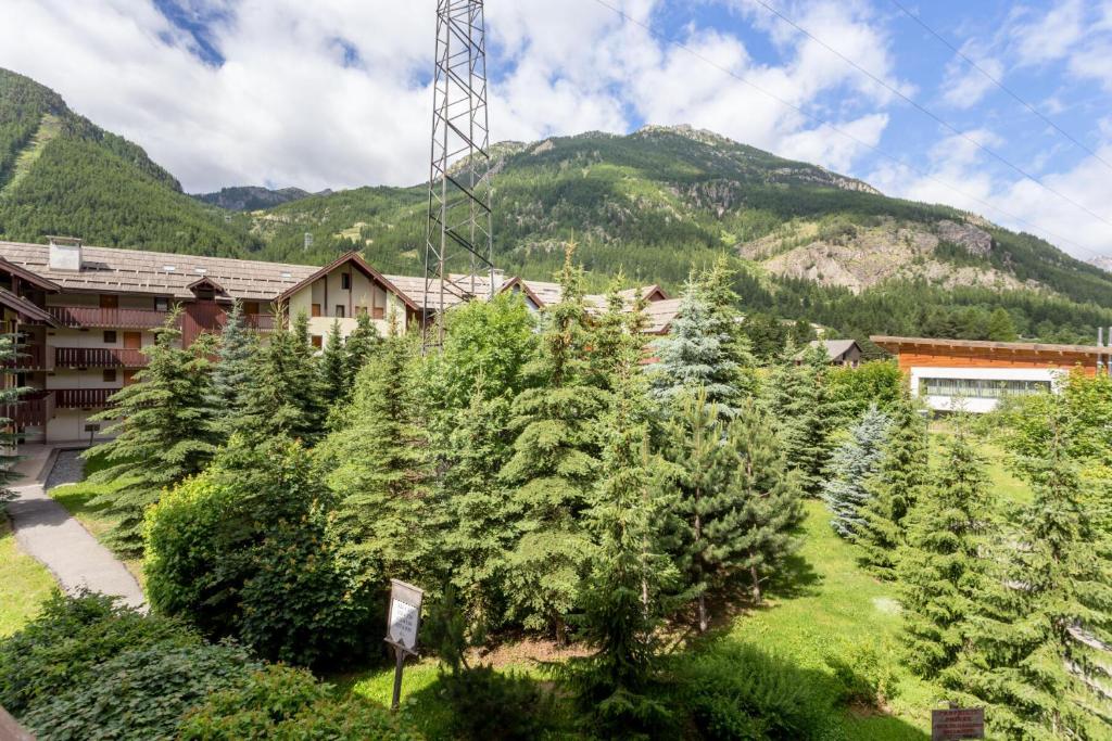 un complexe avec un tas d'arbres et une montagne dans l'établissement Résidence L'Alpaga - maeva Home - Appartement 2 Pièces 5 Personnes - Budget MAE-2484, à La Salle Les Alpes