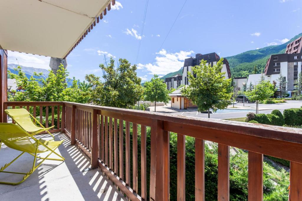 a balcony with a yellow chair and a view of a street at Résidence L'Alpaga - maeva Home - Appartement 2 Pièces 7 Personnes - Budge 524 in La Salle-les-Alpes