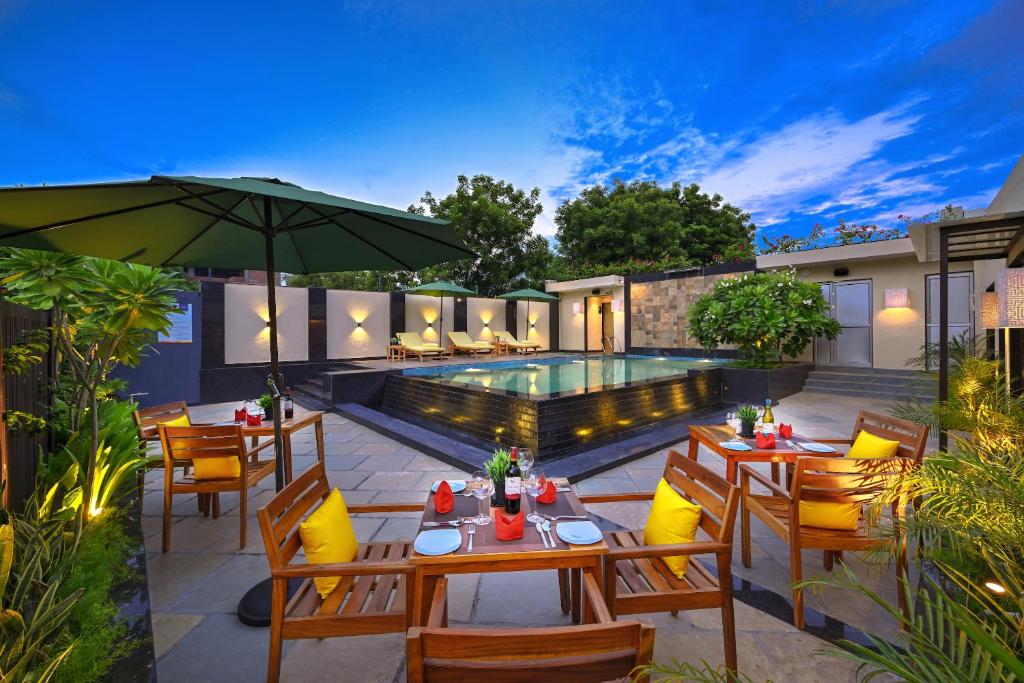 un patio avec des tables et des chaises à côté d'une piscine dans l'établissement Royale Sarovar Portico Agra, à Agra