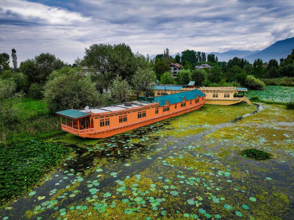 an orange boat on a river with flowers at Kings Houseboats in Srinagar