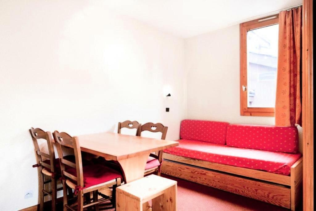 een woonkamer met een rode bank en een tafel bij Résidence Les Chalets des Arolles - maeva Home - Studio 5 Personnes - Séle 004 in La Plagne Tarentaise