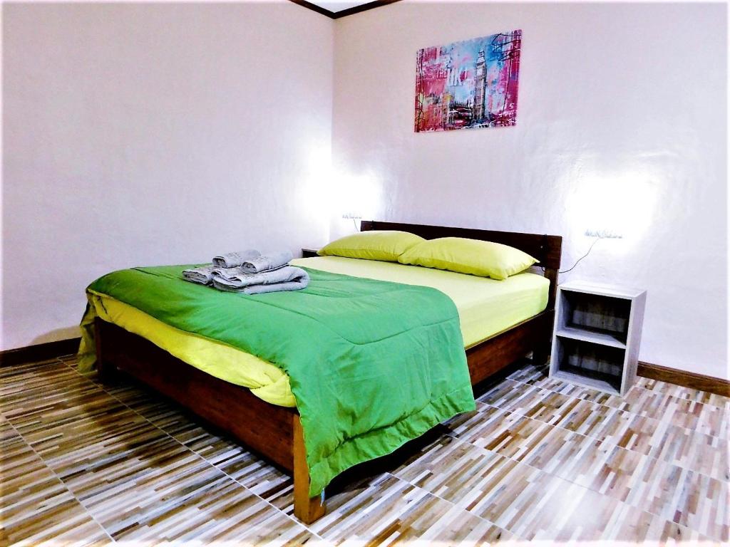 a bedroom with a bed with a green blanket at Swiss Bonihouse Koh Yao Yai in Ban Phlu Nai