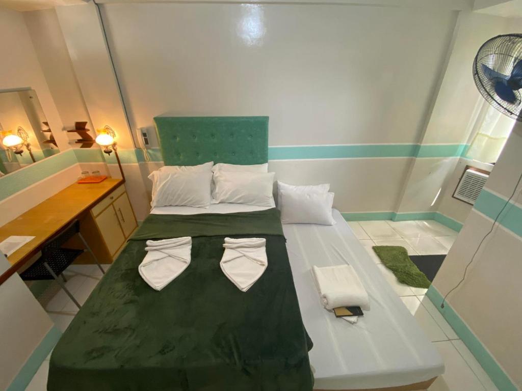 a small bedroom with a green bed with two towels at Casa Marie Hotel in Daet