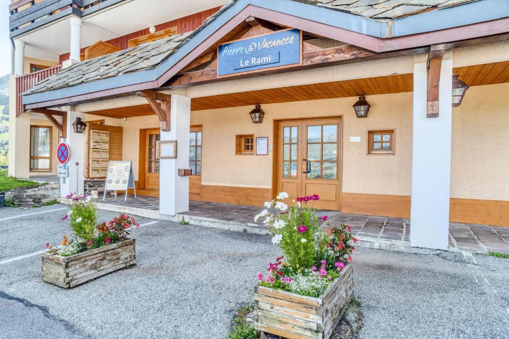 un hôtel avec deux fleurs devant un bâtiment dans l'établissement Résidence La Marelle et Le Rami - maeva Home - Appartement 2 Pièces 7 Personnes - Sélection MAE-7164, à La Plagne Tarentaise