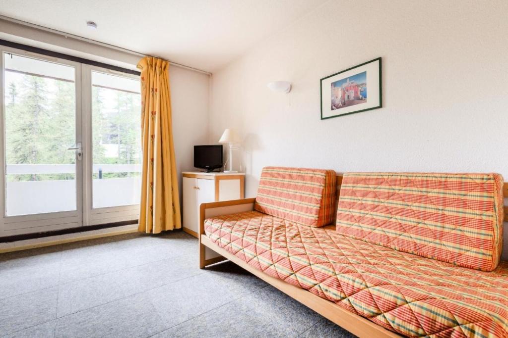 un salon avec un canapé et une fenêtre dans l'établissement Résidence L'Eyssina - maeva Home - Studio 5 Personnes Budget MAE-1945, à Vars