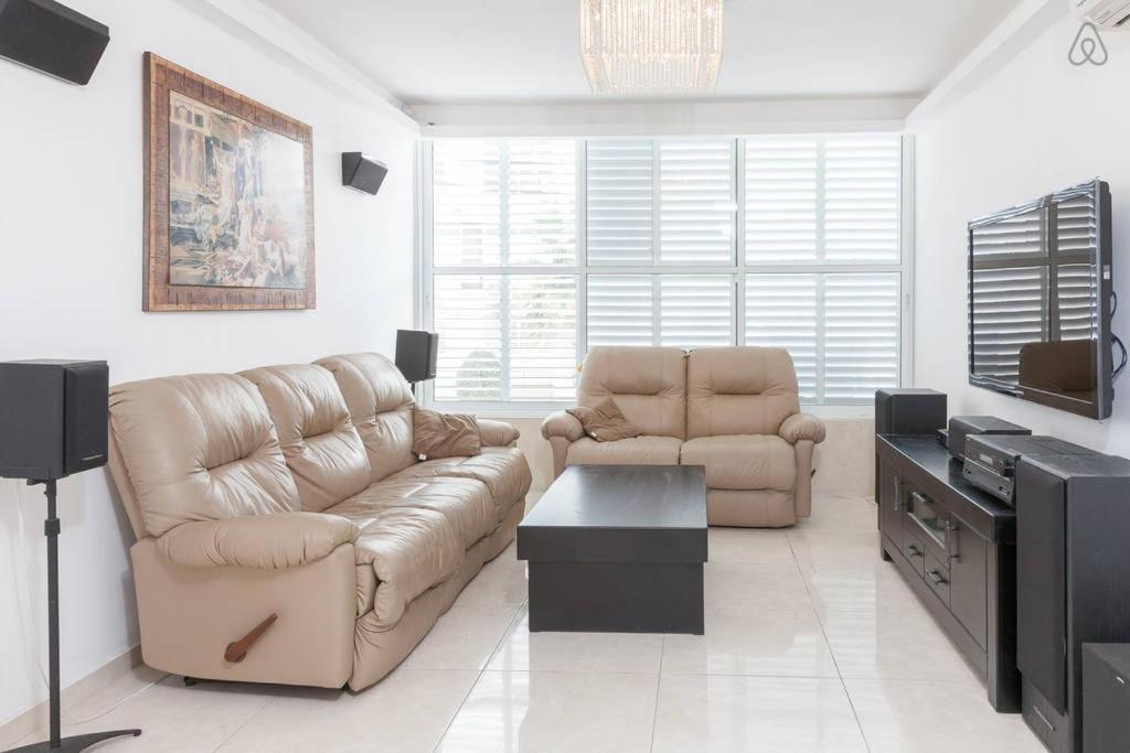 sala de estar con sofá de cuero y TV en Vip Apartment, en Bat Yam
