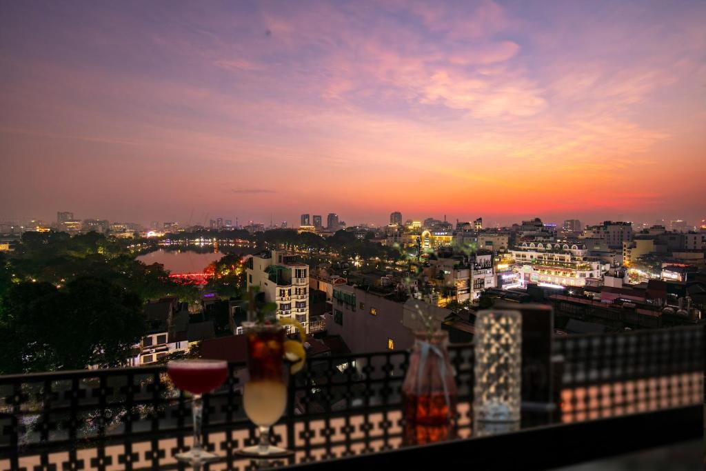 a view of a city at sunset from a balcony at Lucien Hanoi Lakeside Hotel & Rooftop in Hanoi