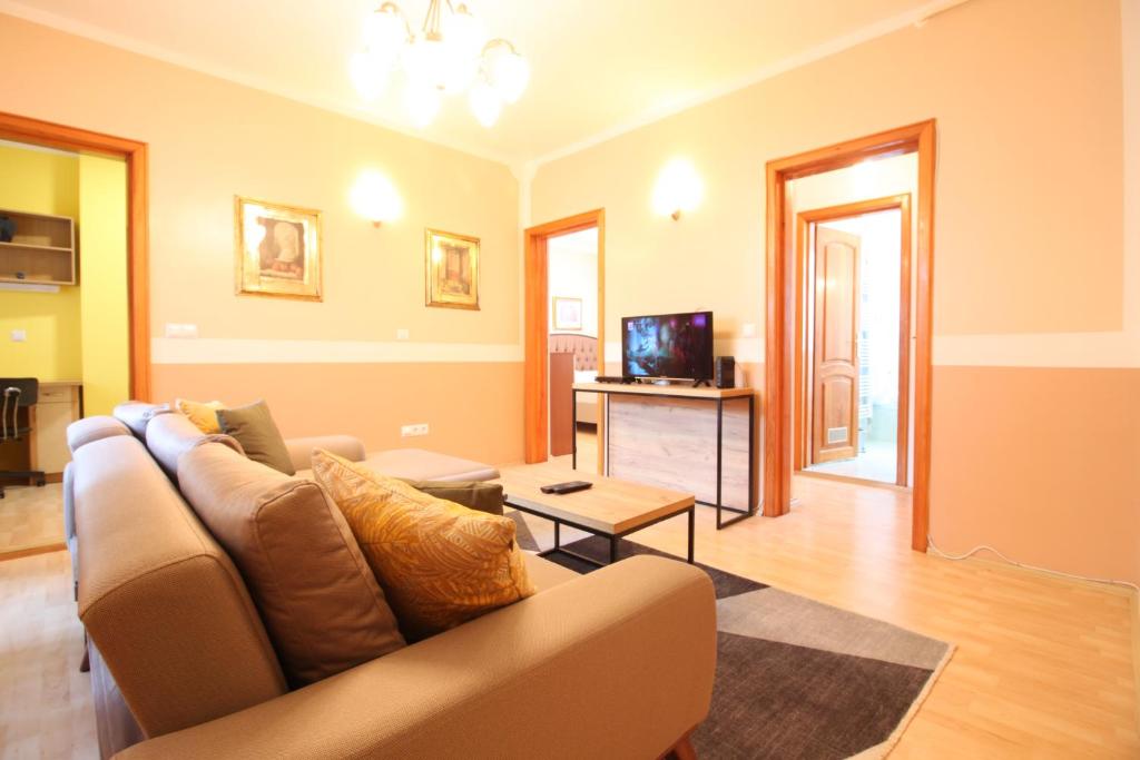 Una sala de estar con un sofá y un televisor. en Retro Apartment, en Sarajevo