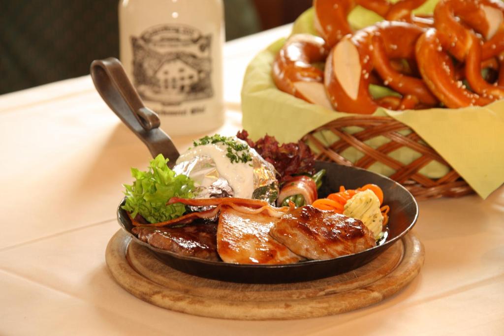 a plate of food on a table with a basket of pretzels at Hotel Klosterhotel Ludwig der Bayer in Ettal