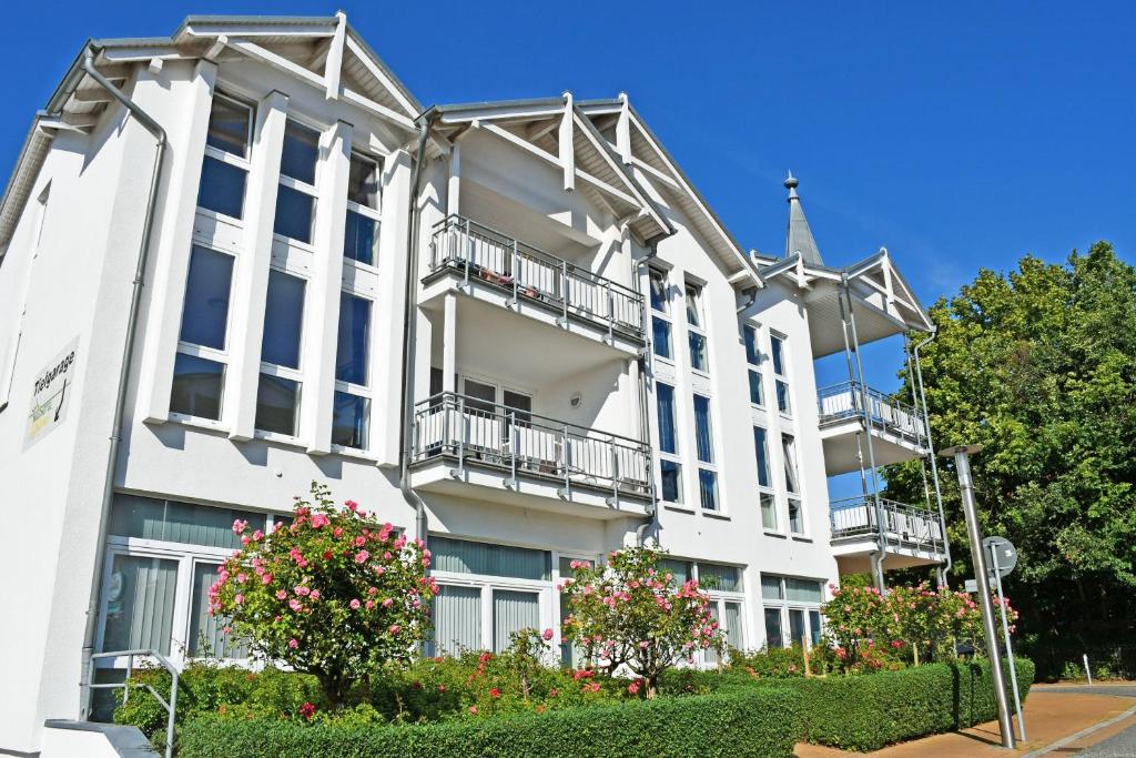 a white building with balconies on a street at Appartementhaus mit Balkon im Ostseebad Göhren HM-01-09 in Göhren