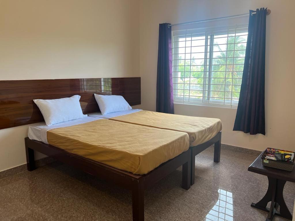 a bedroom with a bed with a wooden headboard and a window at RT Service Apartment Villas in Velankanni