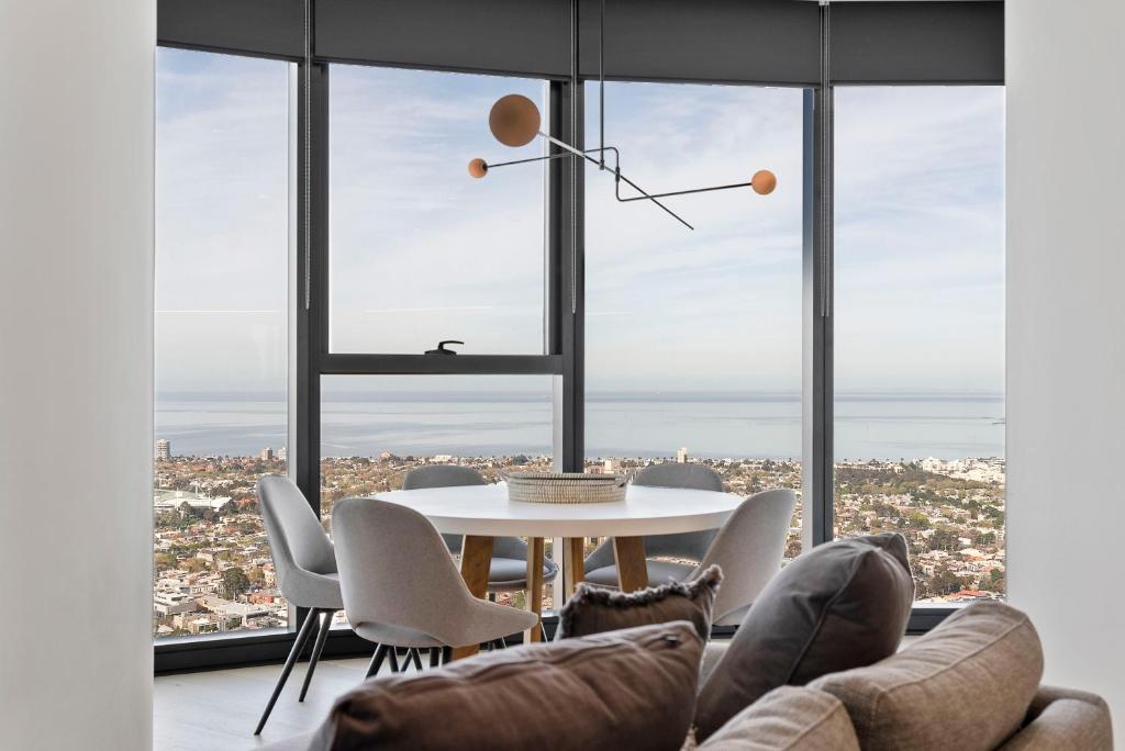 comedor con mesa y sillas y ventana grande en Sub Penthouse Southbank Apartment - 3BR, en Melbourne