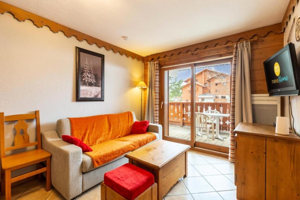 ein Wohnzimmer mit Couch und großem Fenster in der Unterkunft Résidence Les Fermes du Soleil - maeva Home - Appartement 3 pièces 6 personnes - Sélection MAE-8007 in Les Carroz d'Araches