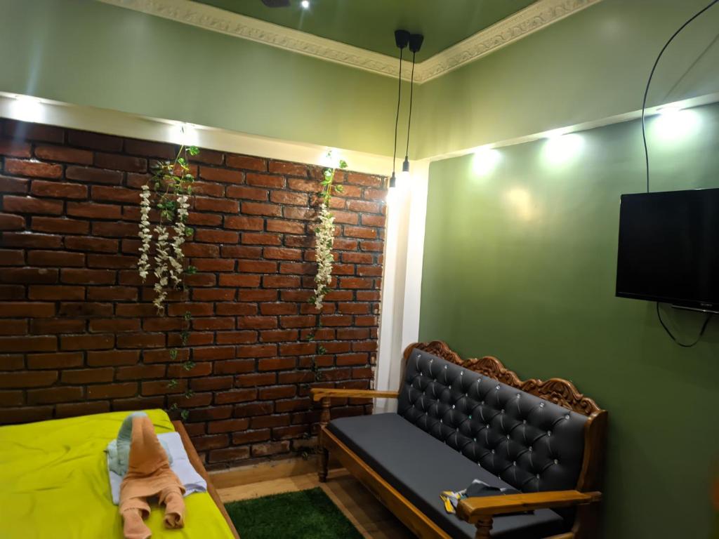 a room with a couch and a brick wall at Budget-Friendly Luxury Air-Conditioned Deluxe Suite at Pravuprasad Homestay in Bhubaneshwar