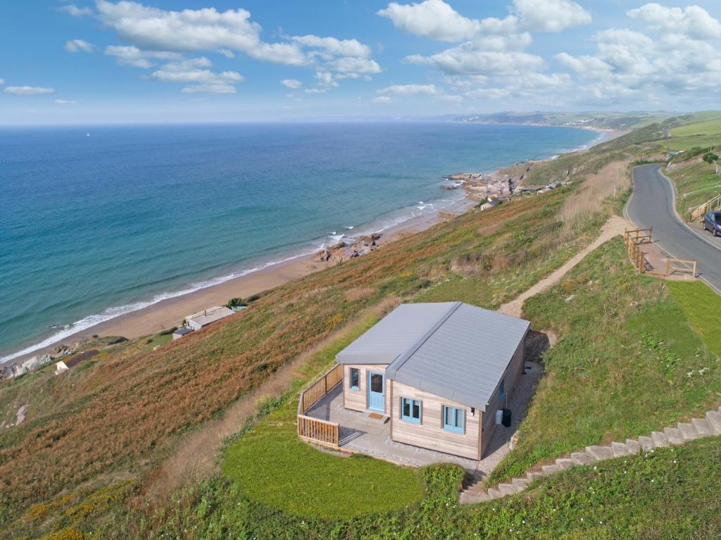 an aerial view of a house on a hill next to the ocean at Solana in Torpoint