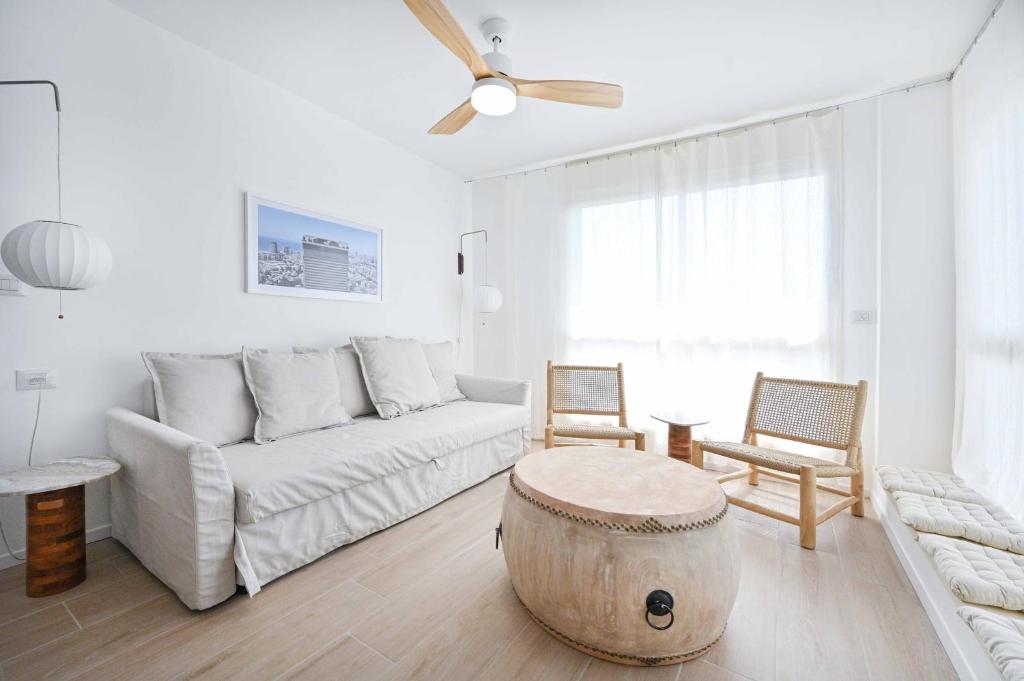 ein Wohnzimmer mit einem weißen Sofa und Holzboden in der Unterkunft The Levana 3BR Duplex Penthouse by HolyGuest in Tel Aviv