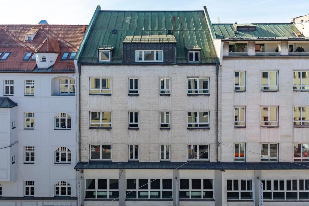 um edifício alto com um telhado verde em numa I Blend Apartments em Munique