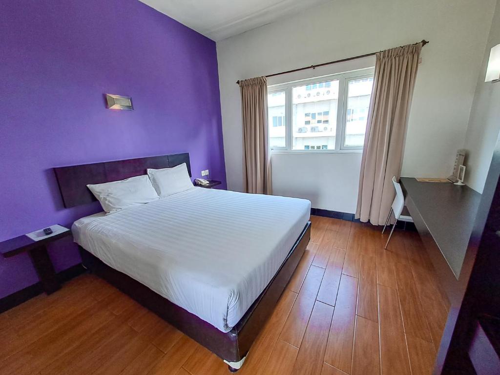 HOTEL TILAMAS في Dares: غرفة نوم بسرير ابيض وجدار ارجواني