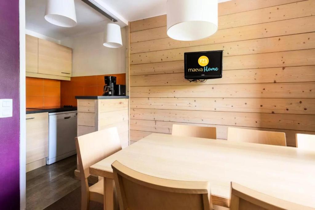 a kitchen with a table and a television on a wall at Résidence Plagne Lauze - maeva Home - Appartement 3 pièces 7 personnes - S 954 in Mâcot La Plagne