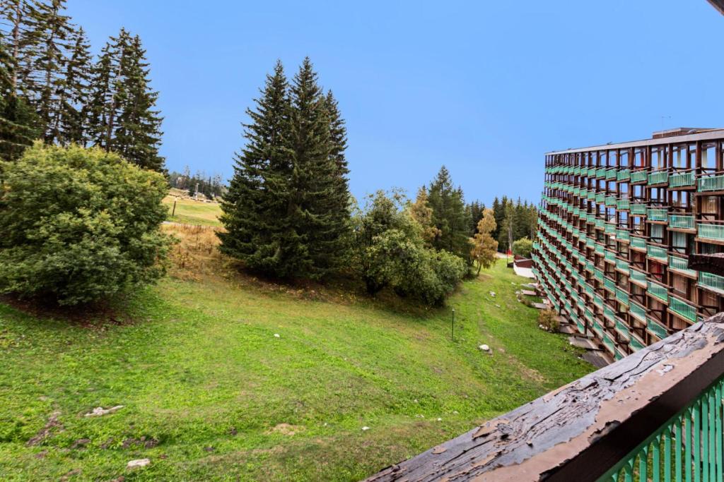 un bâtiment sur une colline à côté d'un champ arboré dans l'établissement Résidence les Lauzières - maeva Home - Studio 5 personnes - Confort MAE-4424, à Arc 1800