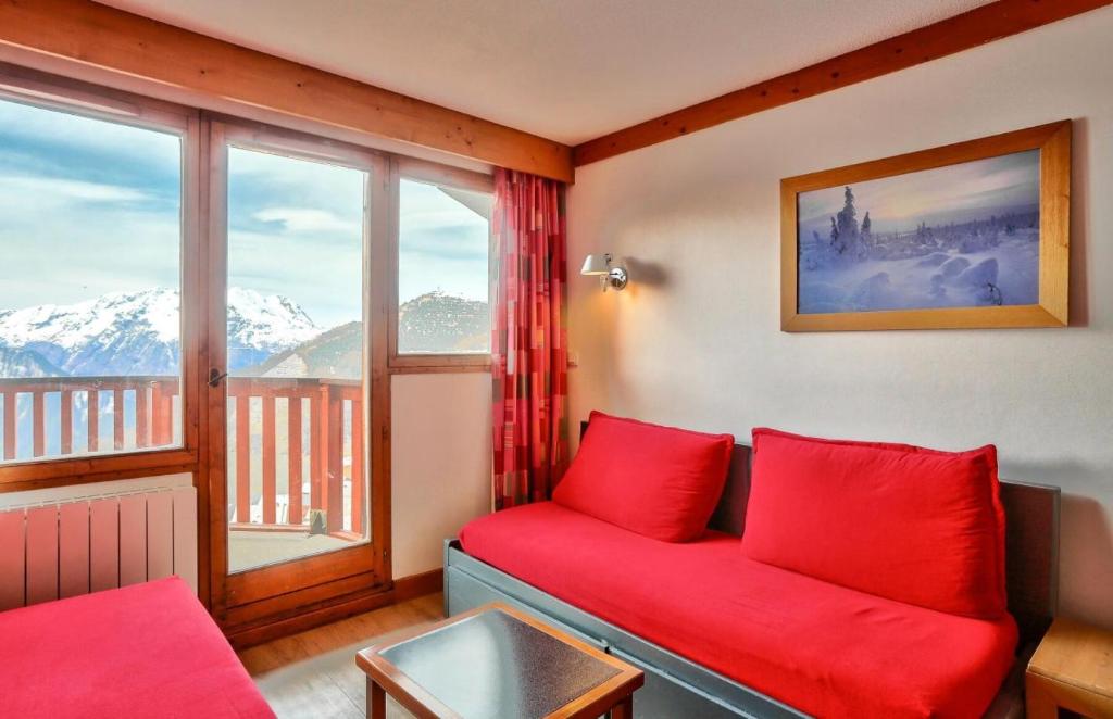 een woonkamer met een rode bank voor een raam bij Résidence L'Ours Blanc - maeva Home - Appartement 3 pièces 7 personnes - C 494 in Huez