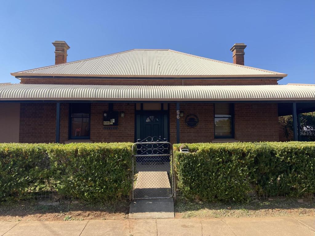 une maison en briques avec des haies devant elle dans l'établissement Perrington Estate, à Nyngan