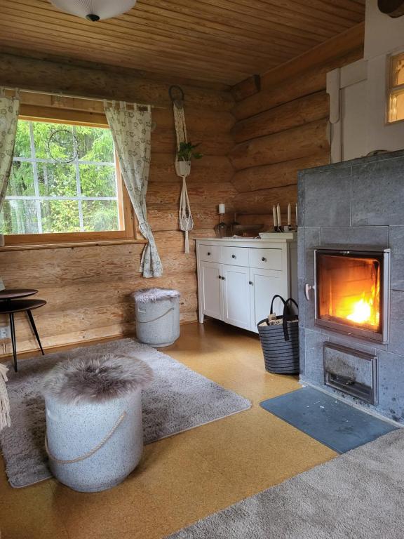 Hirsitalo ja -sauna في Nummi: غرفة معيشة مع موقد في كابينة خشب