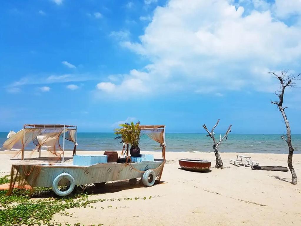 un coche viejo aparcado en una playa con el océano en Hotel Việt Sang, en La Gi