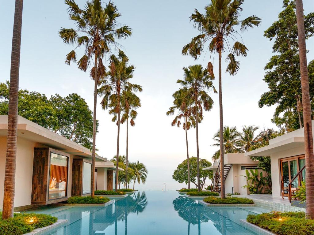 um resort com palmeiras e uma piscina em RELO' The Urban Escape - Huahin em Cha Am