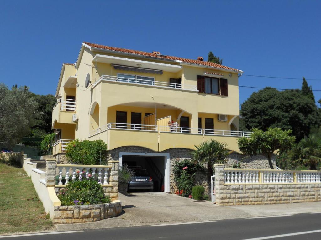 a large yellow house with a car garage at Apartments Gržanov in Sutomišćica