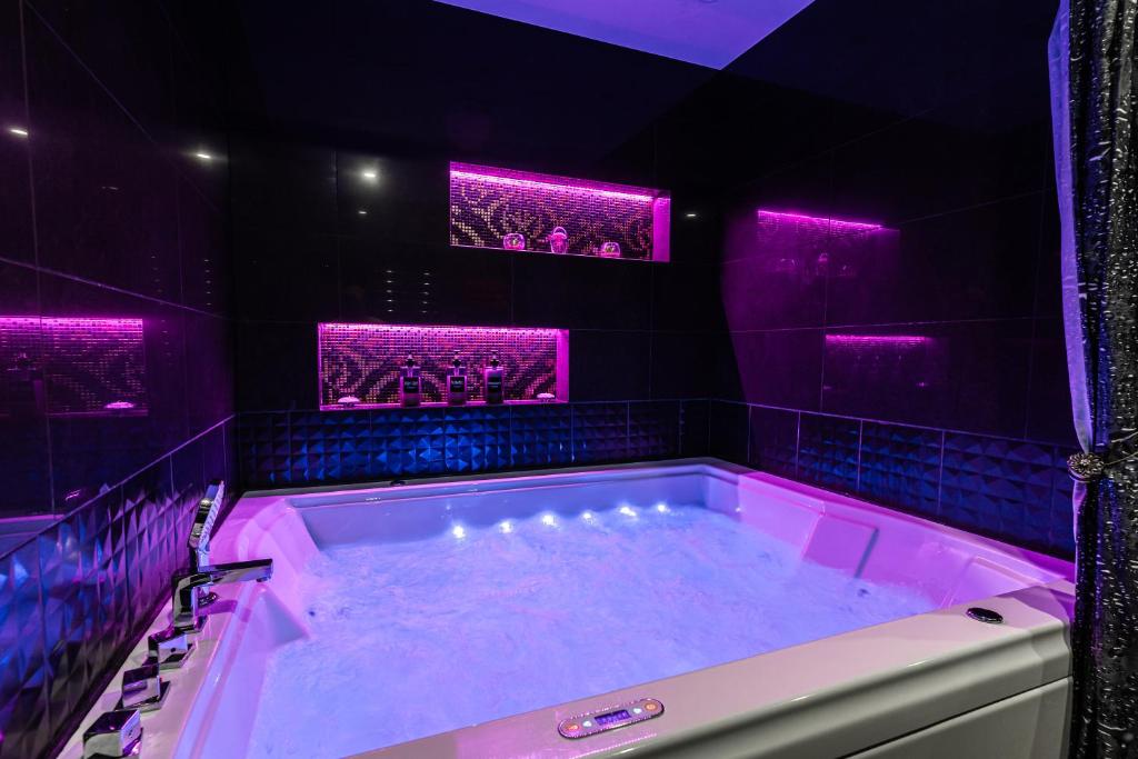 LuxeCityApartment في تالين: حمام أرجواني مع حوض مع أضواء أرجوانية