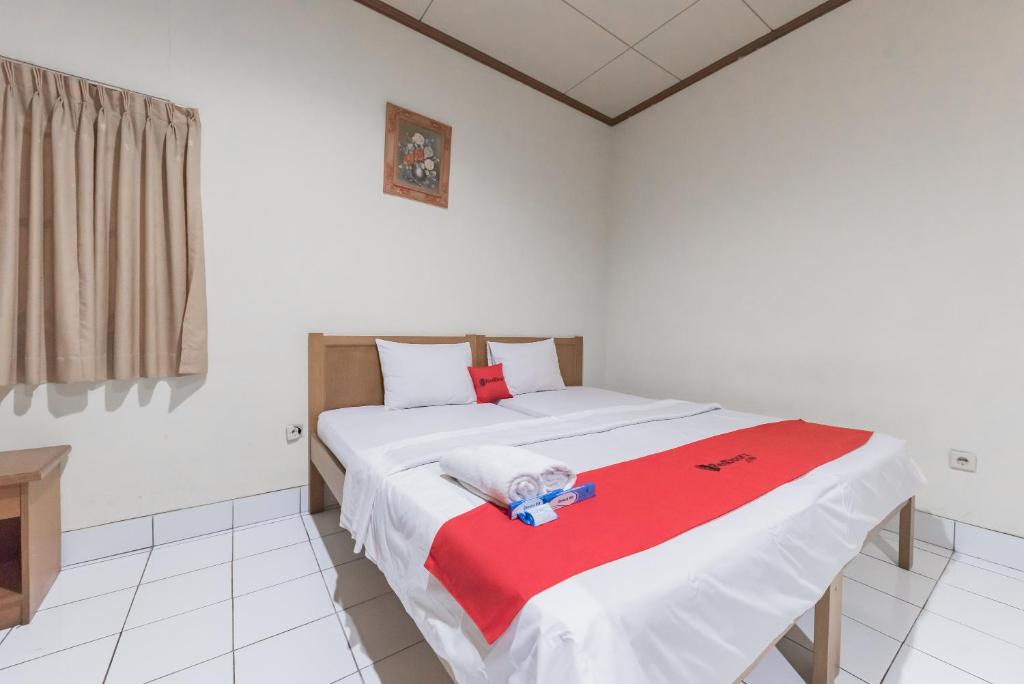 - un petit enfant assis sur un lit dans une chambre dans l'établissement RedDoorz Plus At Hotel Griya Astoeti, à Bogor