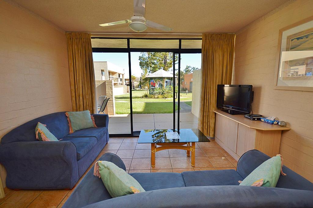 a living room with two blue couches and a tv at Riverview Holiday Apartment 47 - Kalbarri, WA in Kalbarri