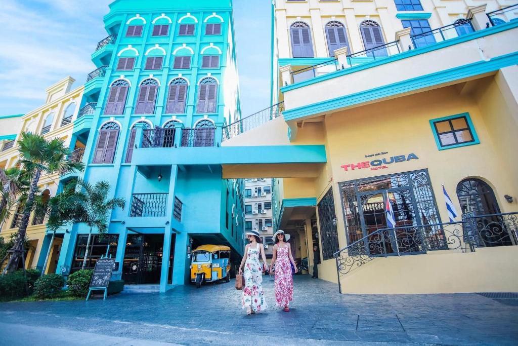 The Quba Boutique Hotel Pattaya by Compass Hospitality في باتايا سنترال: سيدتان تتمشيان أمام مبنى