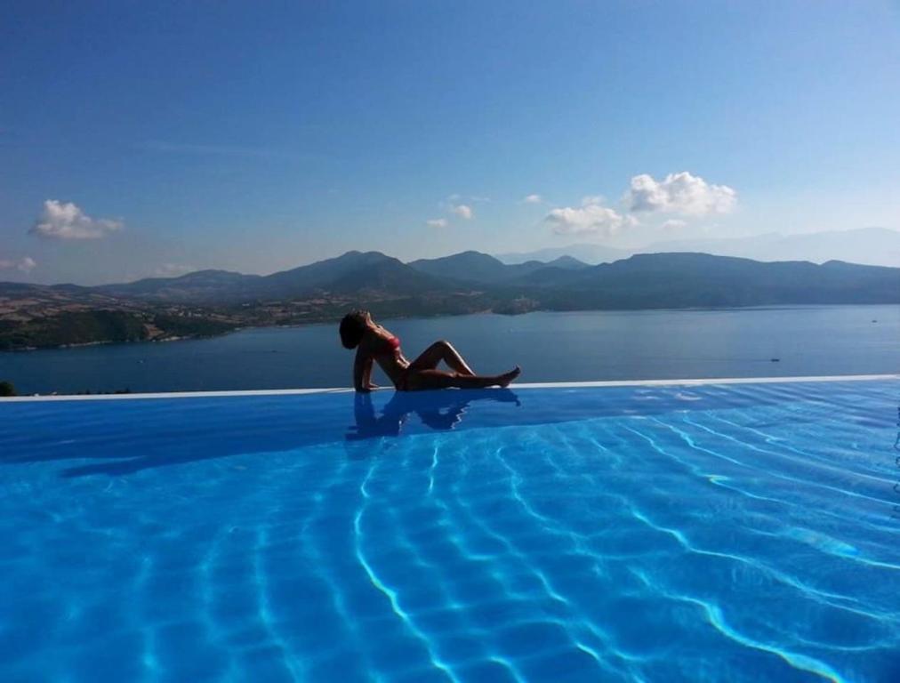 a woman sitting on the edge of a swimming pool at THEARESORT EXCLUSIVE in Lygia