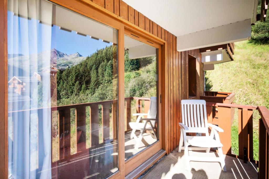 a screened porch with two chairs and a view of the mountains at Résidence Les Crêts - maeva Home - 3 Pièces 6 Personnes Selection 26 in Les Allues