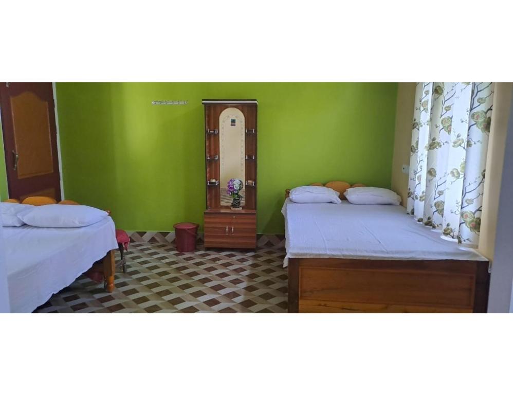 two beds in a room with green walls at Myna Eco Camp, Raghabbil, Assam in Jyoti Gaon